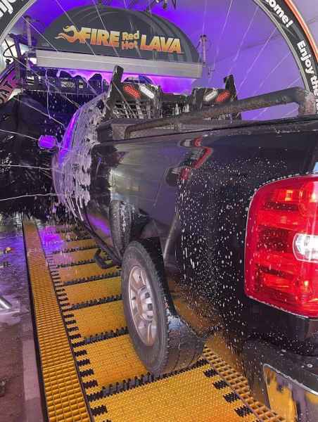 Black truck on conveyor going through soap stage in car wash
