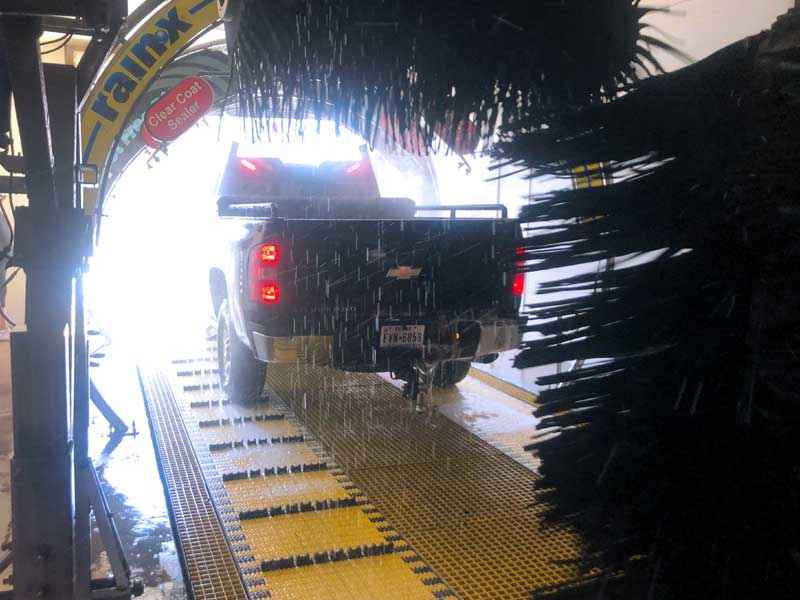 Back view of a black truck in a car wash