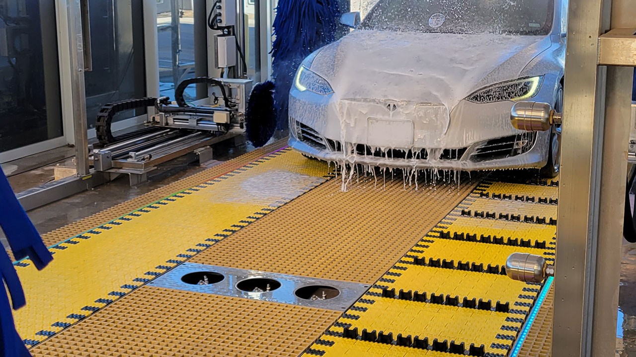 White car on yellow belt conveyor in car wash